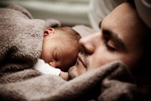 Close up of man holding a sleeping baby; representing Liquidity of short-term investments (money when you need it)