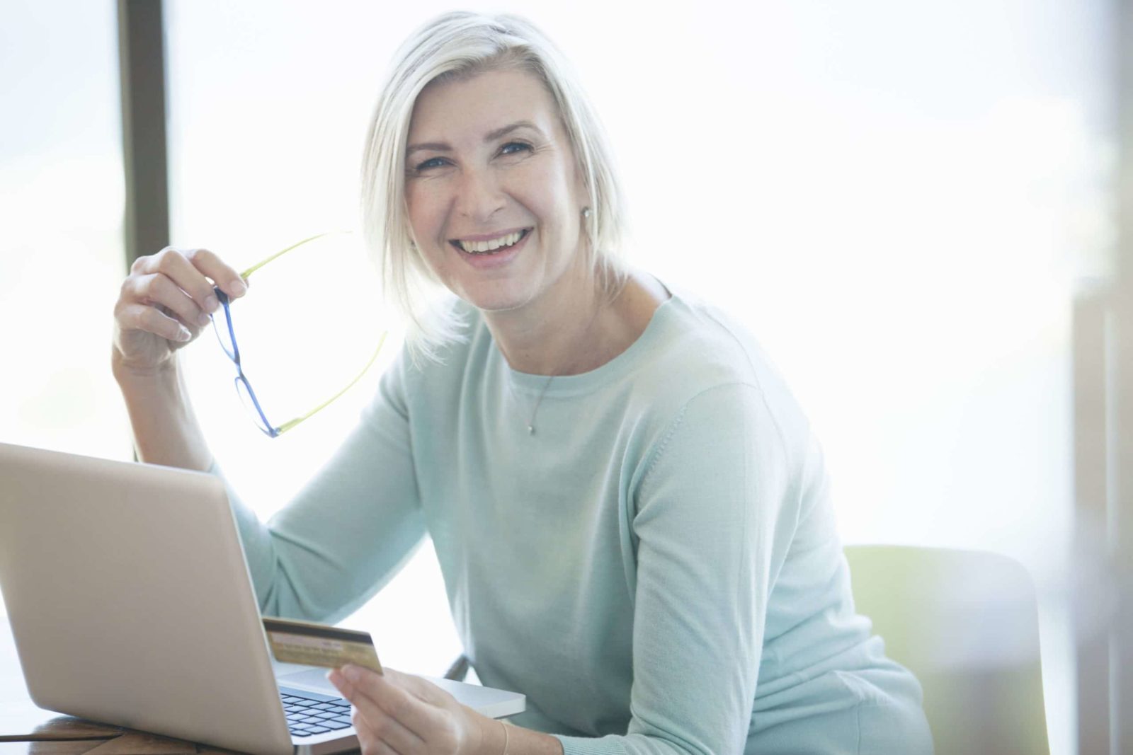 Older woman working on computer, smiling at camera; representing a late in life career change