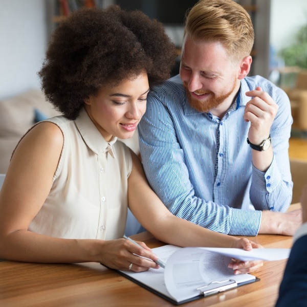 Young couple signing documents representing Risk Management